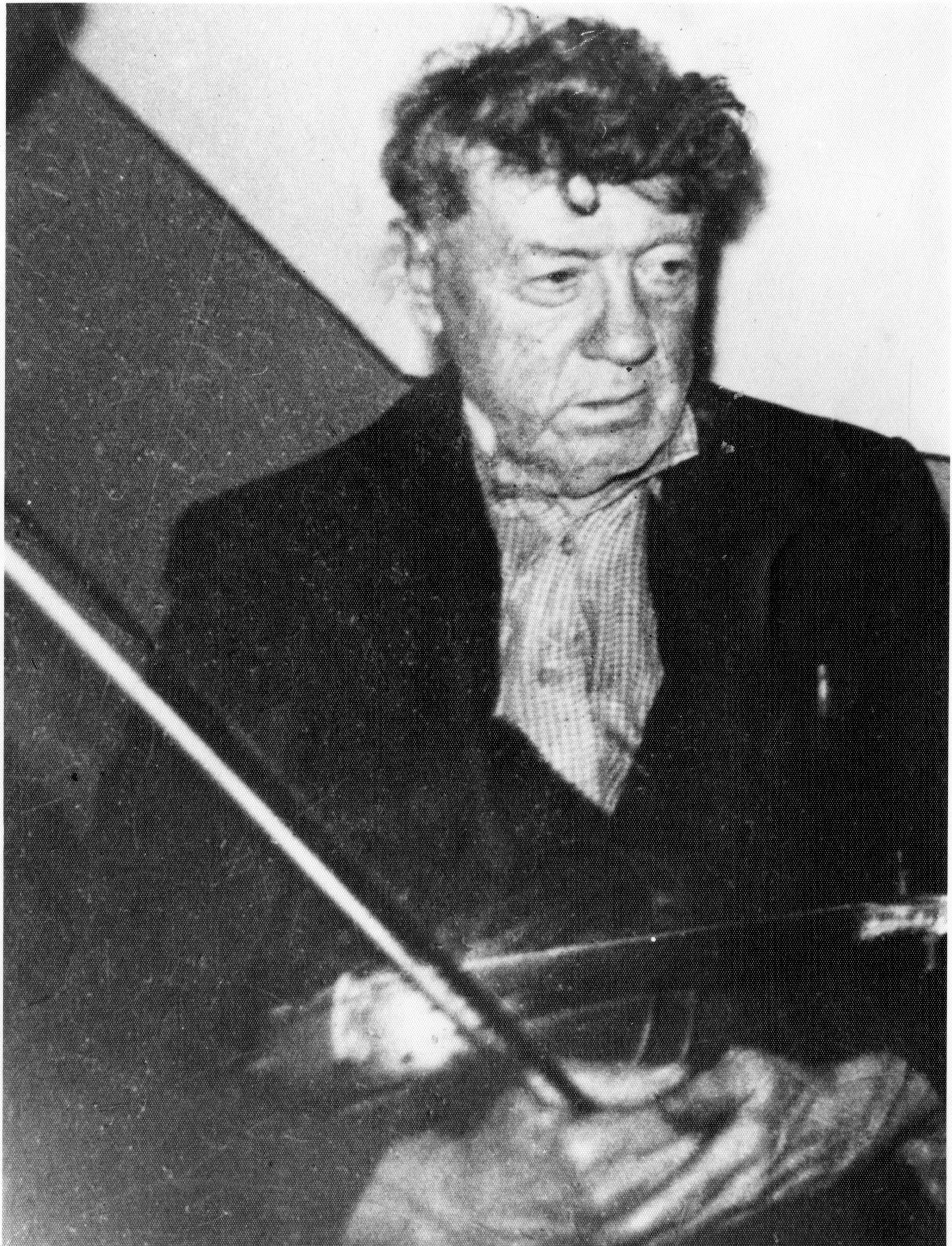 A blurry, black and white photo of a man holding a fiddle.