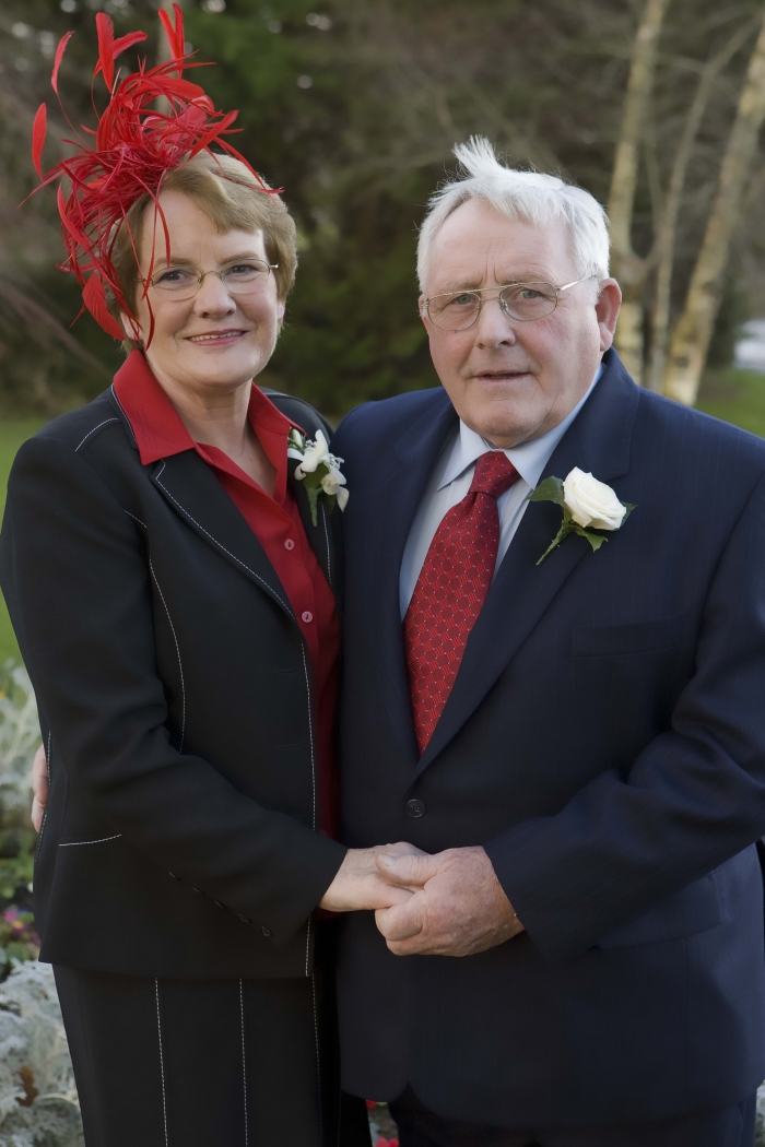 an elderly man and women standing together in formal attire